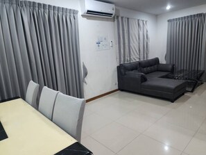 A modern living room with a sectional sofa, a dining table with chairs, and grey curtains.