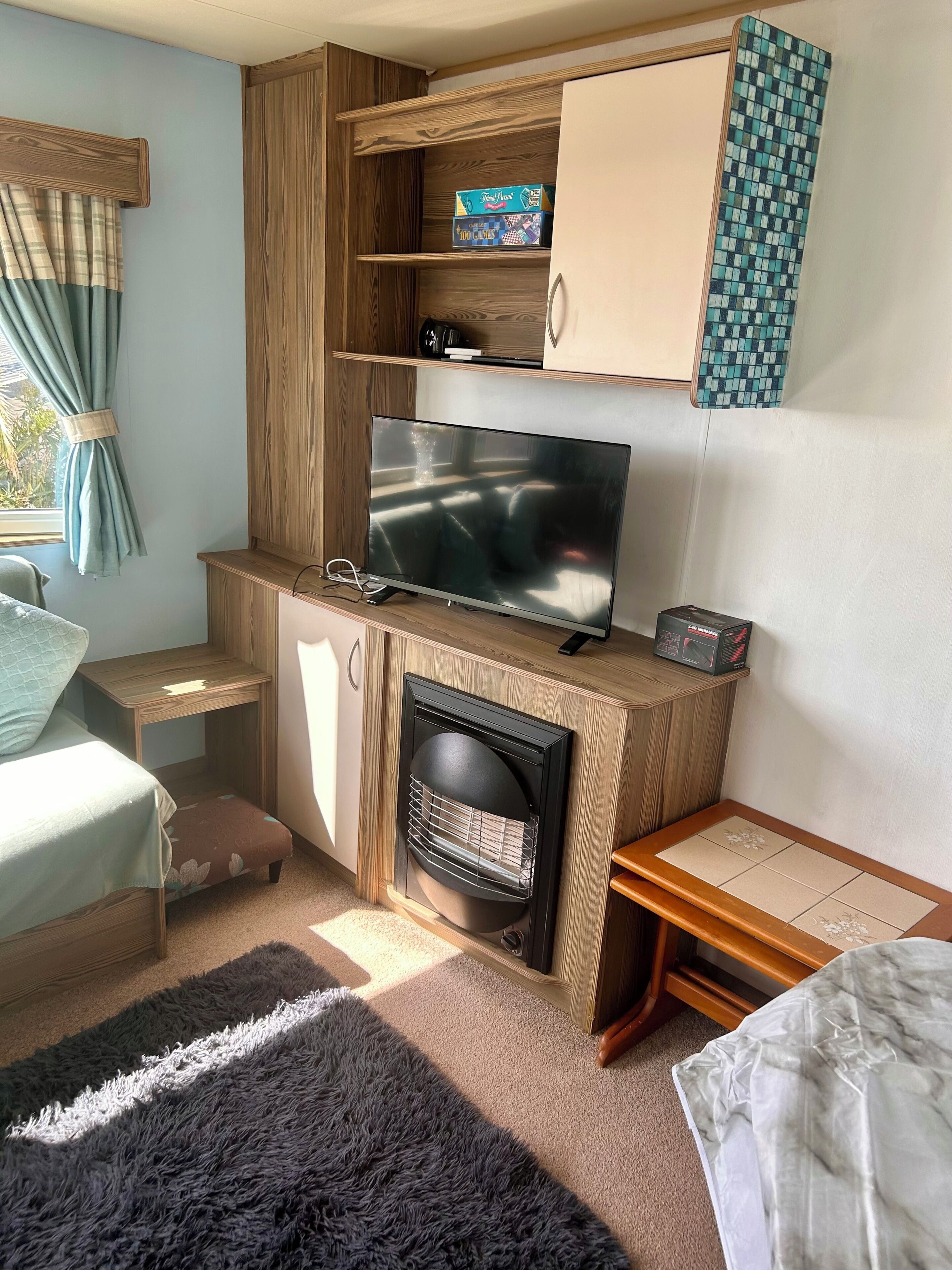 A compact room with a television, a fireplace, a small table, and a bed.