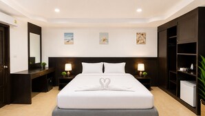 A hotel room with a large bed, two bedside tables with lamps, a wardrobe, and a small refrigerator. - Charming Guest Room in Central Pa Tong, Thailand (Pa Tong)
