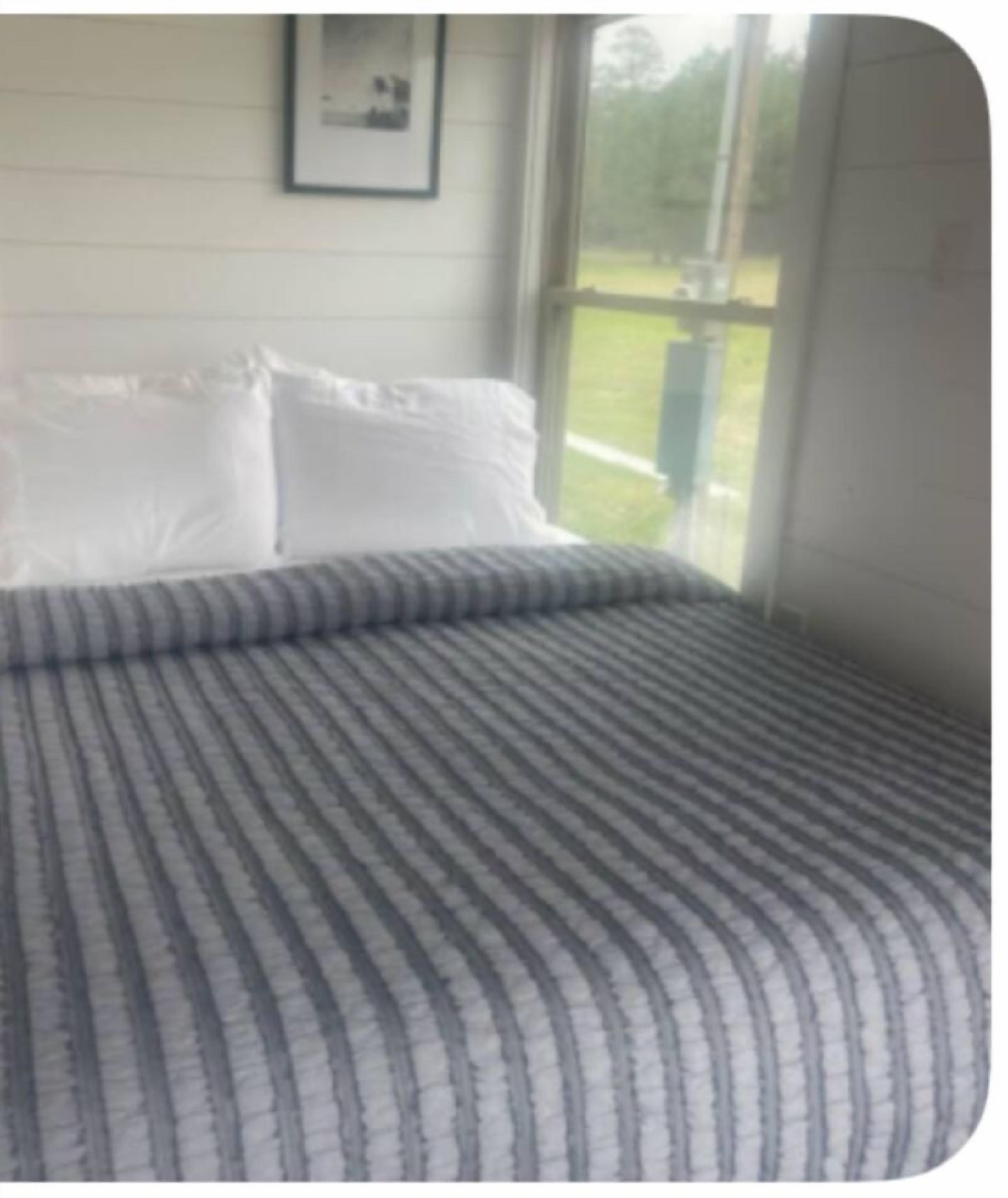A bedroom with a bed, white pillows, and a window with a view of greenery.