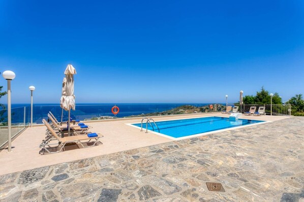 A rooftop pool with clear blue water, sun loungers, and a view of the sea.