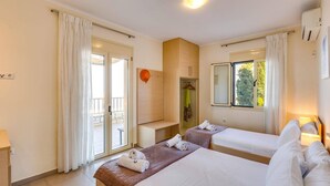 A hotel room with two beds, a bathroom, and a balcony.