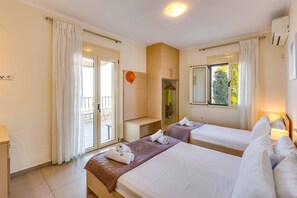 A hotel room with two beds, a bathroom, and a balcony.