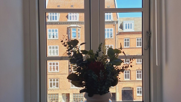Una ventana que muestra vista de un edificio de ladrillo con varias ventanas y balcones.