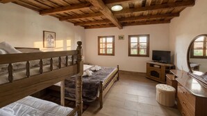 A bedroom with a bunk bed, a single bed, a TV, a dresser, and a mirror.
