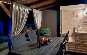 A cozy room with a wooden table, chairs, a bottle, and a fruit basket.