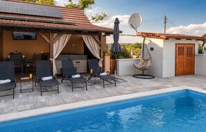A poolside area with lounge chairs, a hot tub, and a hanging chair.