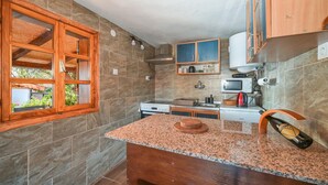 A kitchen with granite countertops, wooden cabinets, a stove, a microwave, and a sink.