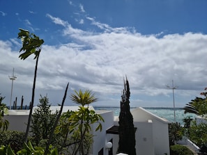 A coastal view with a white building, palm trees, and a clear sky. - Leon Ocean View (Playa Honda)