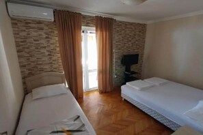 A hotel room with two beds, a television, and a stone-patterned wall.