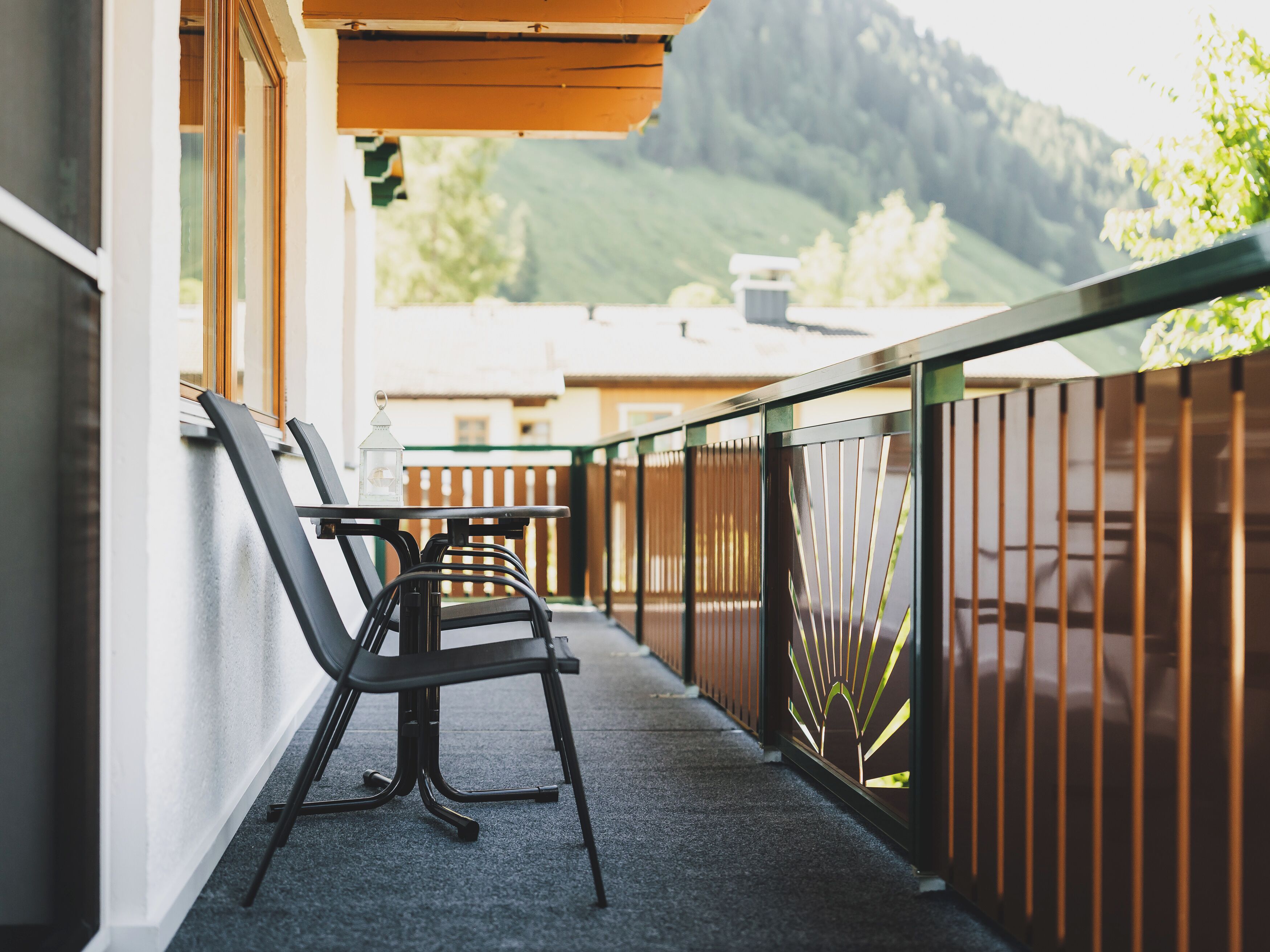 Ein Balkon mit zwei Stühlen, einem kleinen Tisch und einer Laterne.