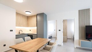 Una cocina moderna con armarios de madera, horno empotrado y zona de comedor con mesa y sillas de madera.
