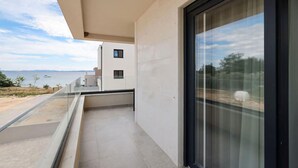 Un balcón moderno con vista al mar y un edificio al fondo.