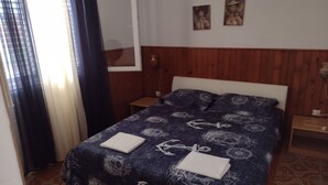 A bedroom with a wooden headboard, a navy blue bedspread with nautical patterns, two bedside tables, and a window with curtains. - Two Bedroom Apartment With Terrace And Sea View (Vela Luka)