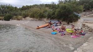 A beach with people sitting on towels and a surfboard. - Two Bedroom Apartment With Terrace And Sea View (Vela Luka)
