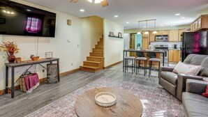 A modern living room with a wooden coffee table, a sofa, and a TV mounted on the wall. - 1 Mi to Main St! Family Farmhouse in West Unity (West Unity)
