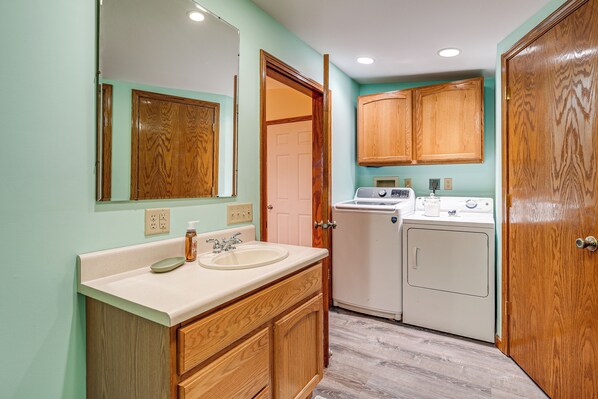 A bathroom with wooden cabinets, a sink, and a washing machine. - 1 Mi to Main St! Family Farmhouse in West Unity (West Unity)