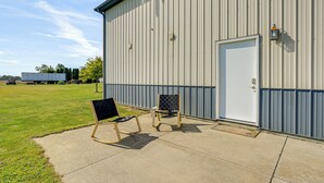 A building with a large door and two outdoor chairs in front. - 1 Mi to Main St! Family Farmhouse in West Unity (West Unity)