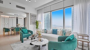 Ein modernes Wohnzimmer mit Türkis-Farbenen Möbeln, einem runden Couchtisch und einem großen Fenster mit Blick auf die Stadt.