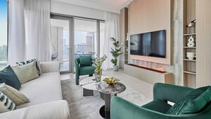 Ein modernes Wohnzimmer mit einer Couch, Sesseln, einem Couchtisch und einem flachbildfernseher an der Wand.
