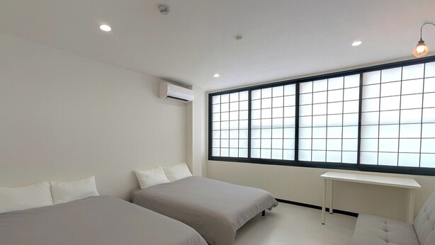 A modern hotel room with two beds, a large window with blinds, a small desk, and an air conditioning unit. - ORIGAMI Stay Osaka (Osaka)