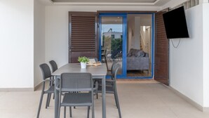 A dining area with a table and chairs, a potted plant, and a sliding glass door leading to a balcony. - Holiday Home 'Oasis 138' with Mountain View, Private Pool and Wi-Fi (Playa Blanca)