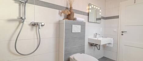 A modern bathroom with a shower, toilet, sink, and a decorative vase.