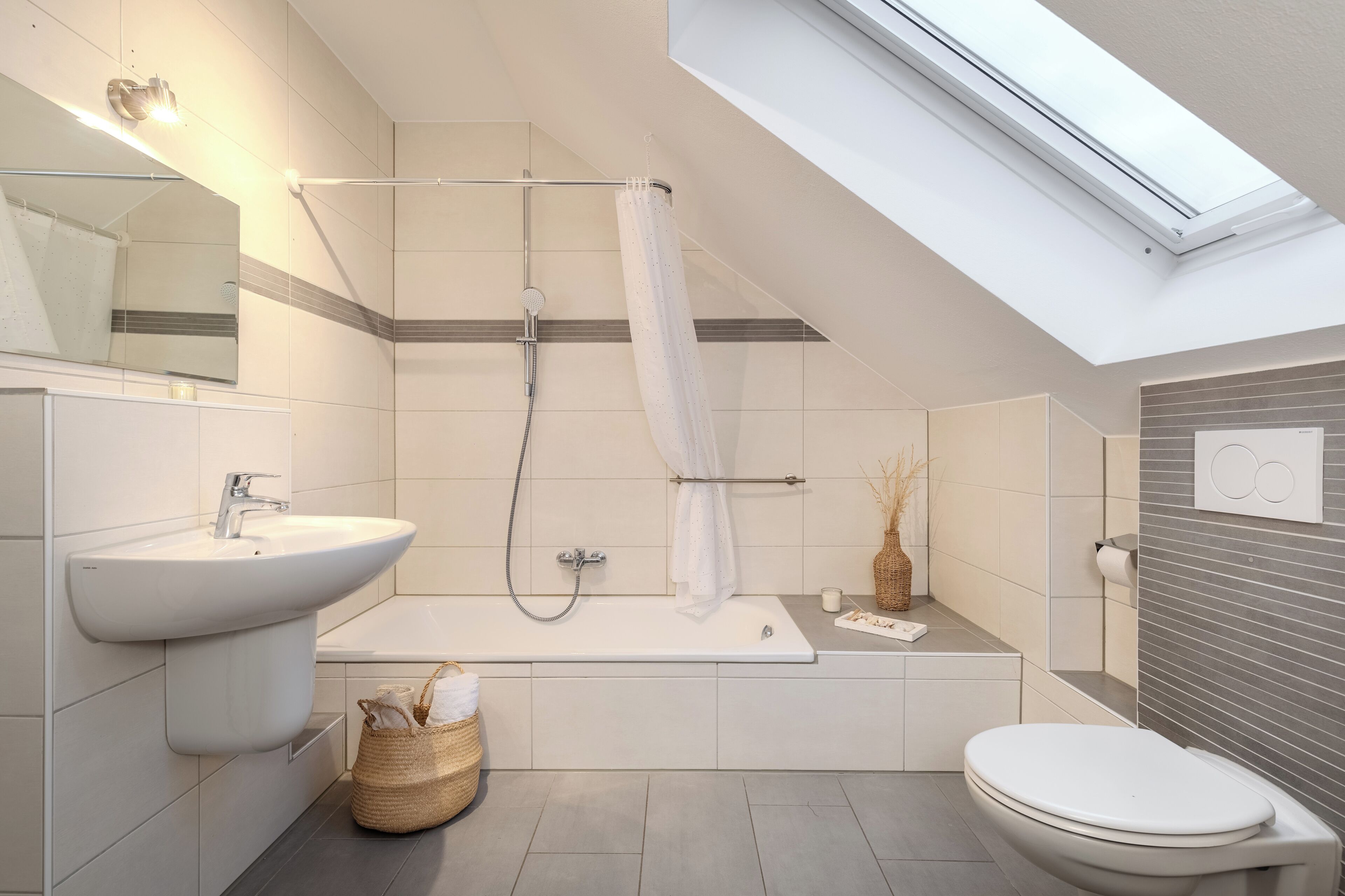 Ein modernes Badezimmer mit Oberlicht, einer Badewanne, einem Waschbecken und einer Toilette.