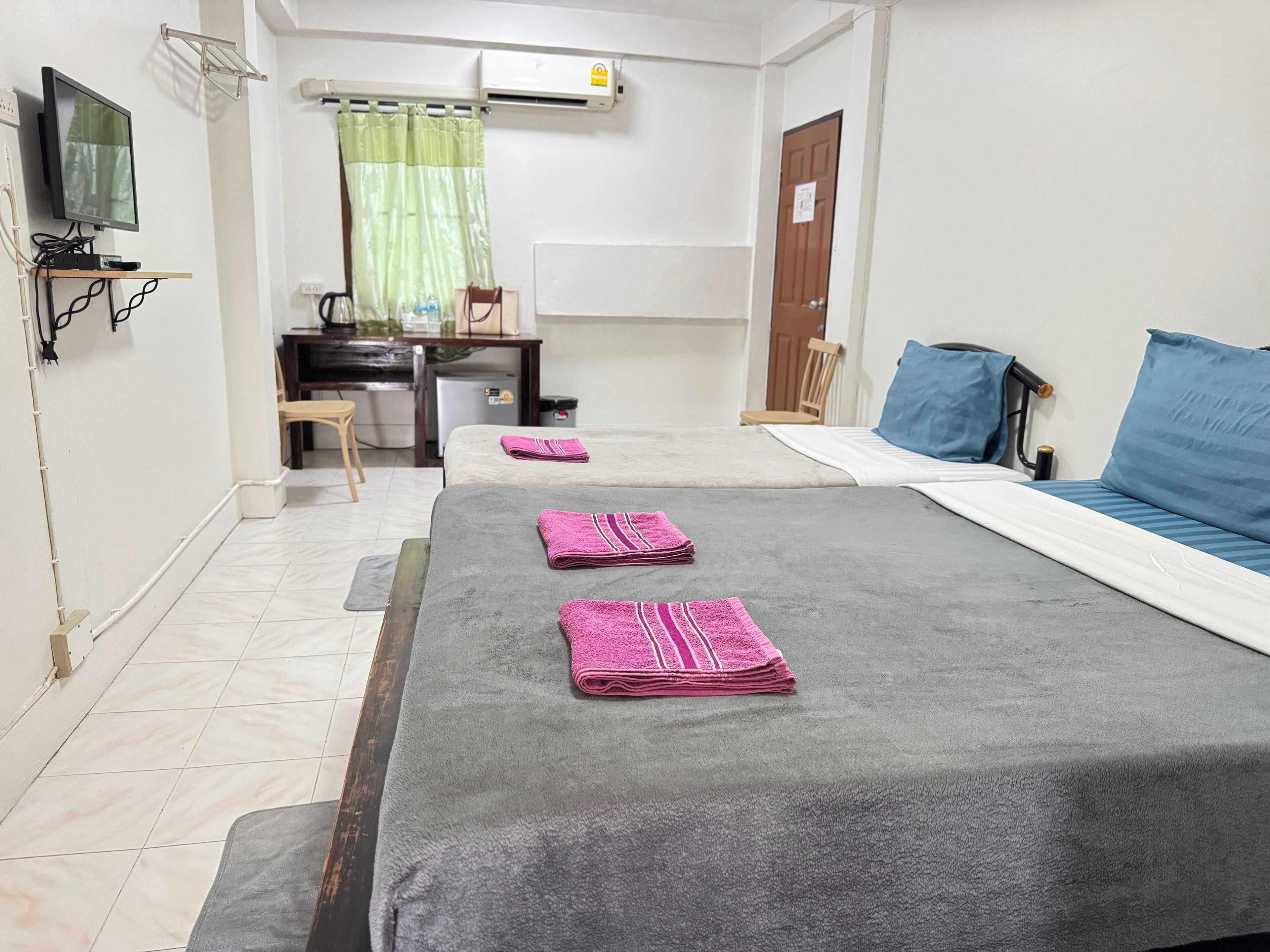 A room with a bed, a desk, a chair, a television, and an air conditioning unit.