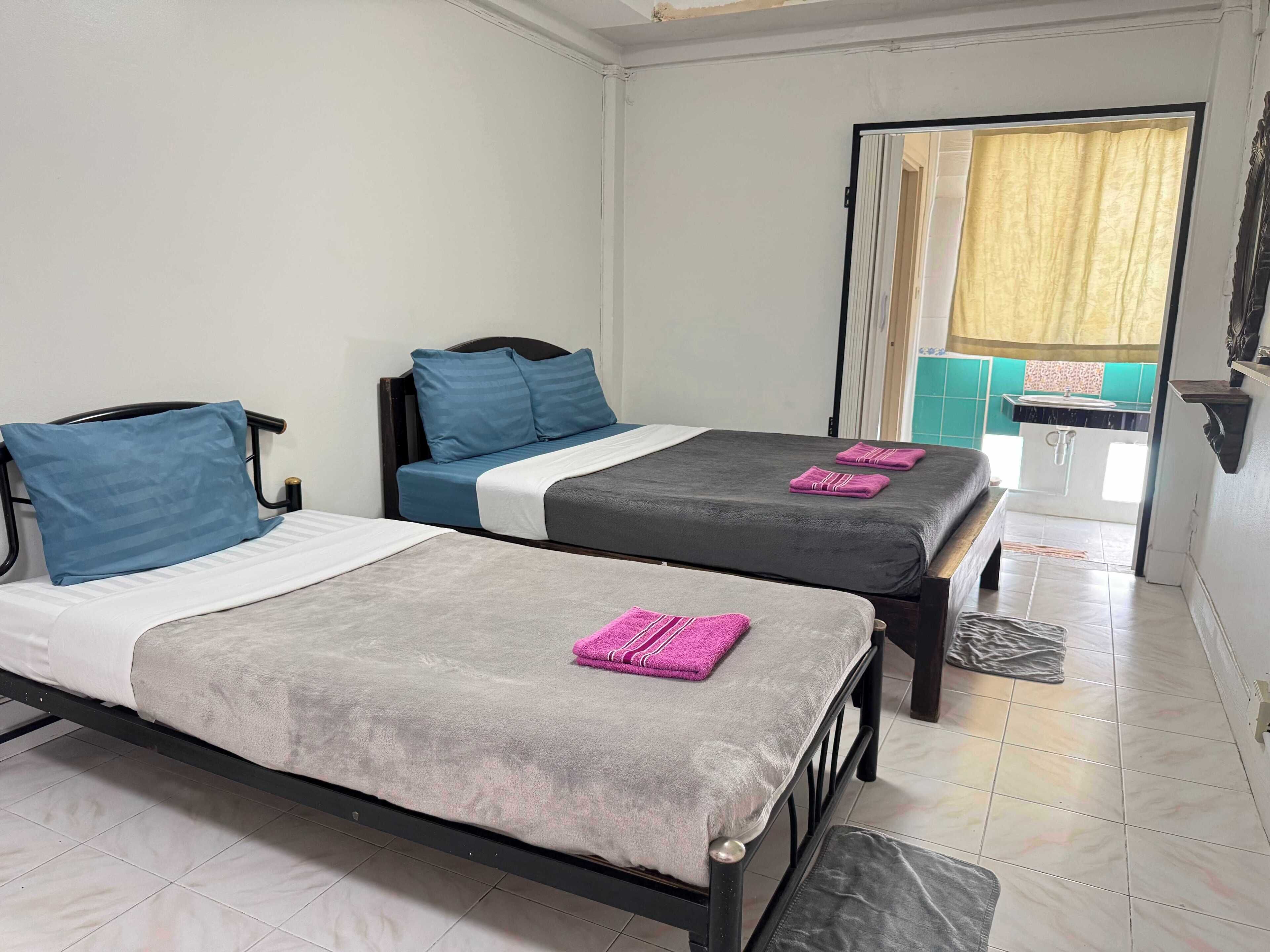 A room with two beds, each with a pillow and a towel.