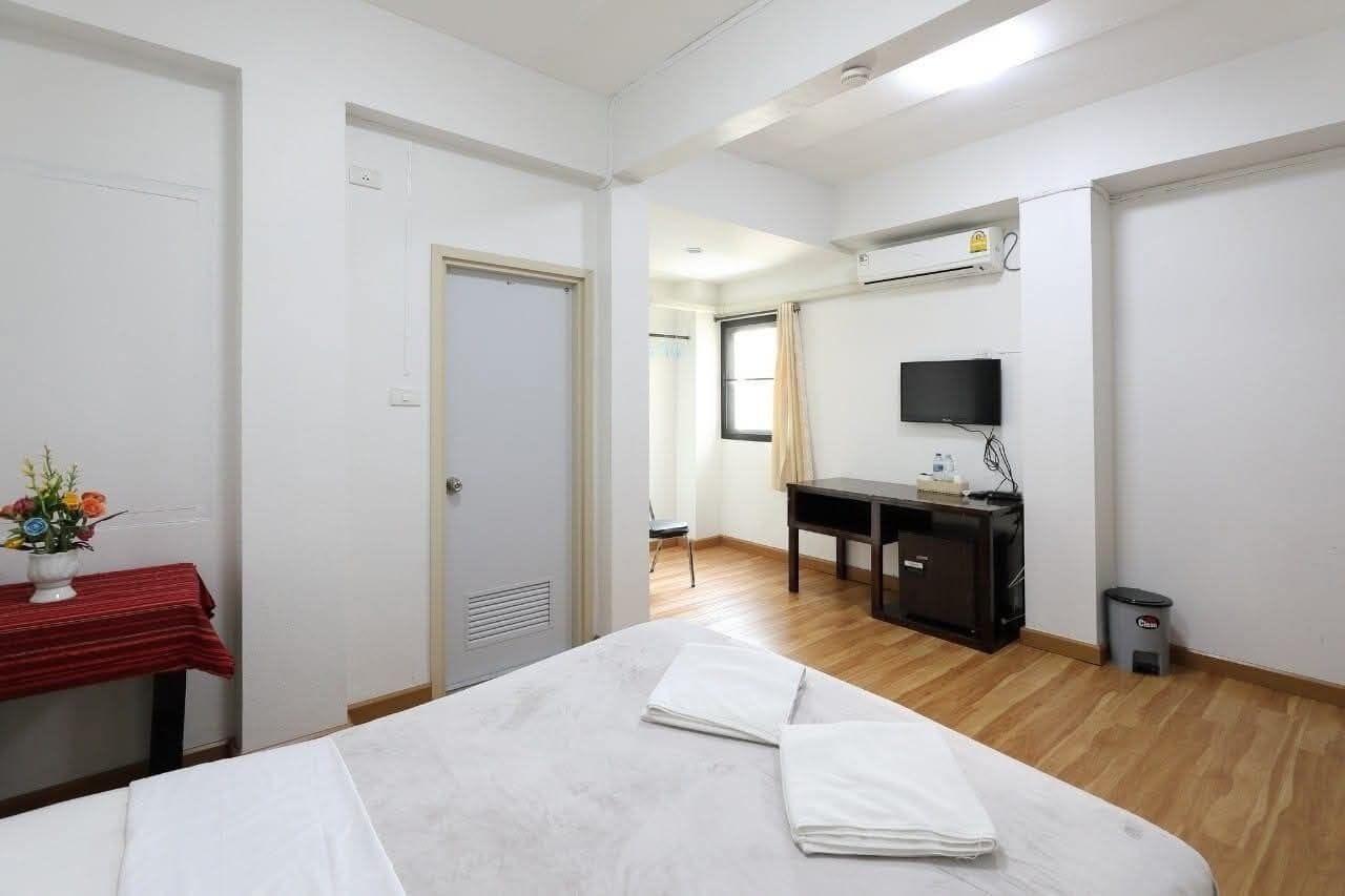 Ett hotellrum med en säng, ett skrivbord, en stol, en tv och en liten papperskorg.