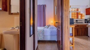 A narrow hallway leading to a bedroom with a bed, a bathroom with a sink, and a kitchenette area. - Cozy & Beautiful Casa Aire, Near Lake Park & Town (Arenal)