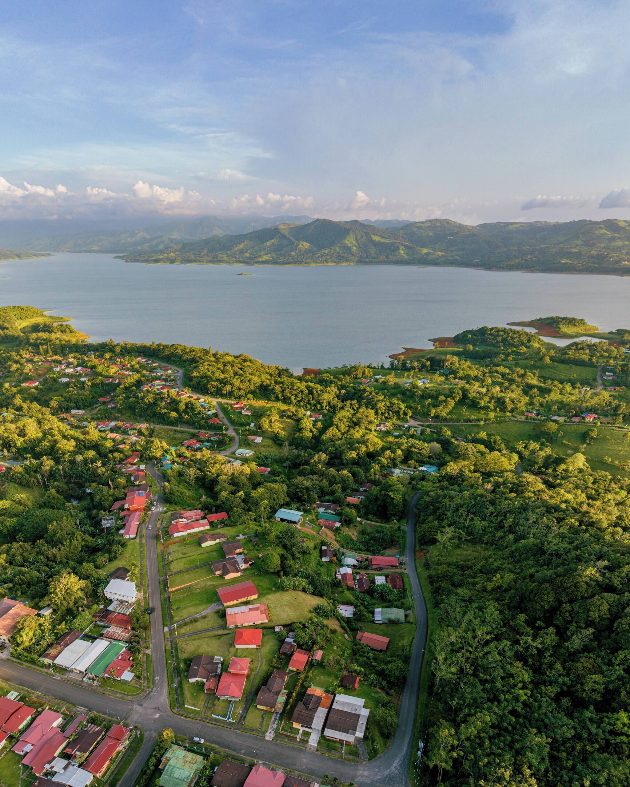 An aerial view of a residential area with houses, roads, and a large body of water in the background.