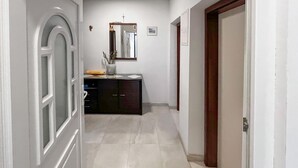 Un passadís amb una porta blanca, un armari de fusta fosca i un mirall a la paret.