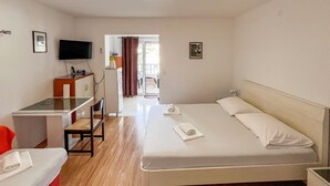 Habitació d'hotel amb un llit, escriptori, cadira i televisió.