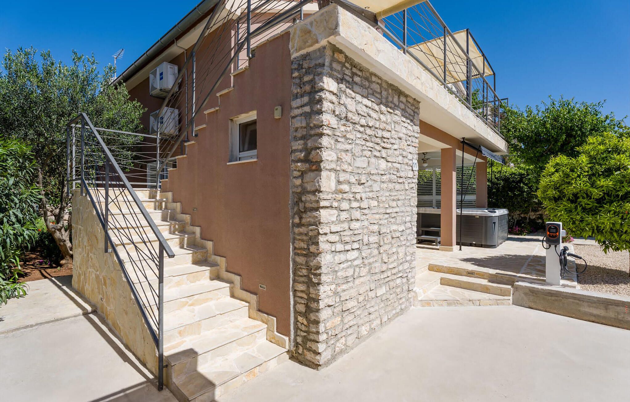 Un edificio de piedra con escaleras, un espacio al aire libre cubierto y un jacuzzi.
