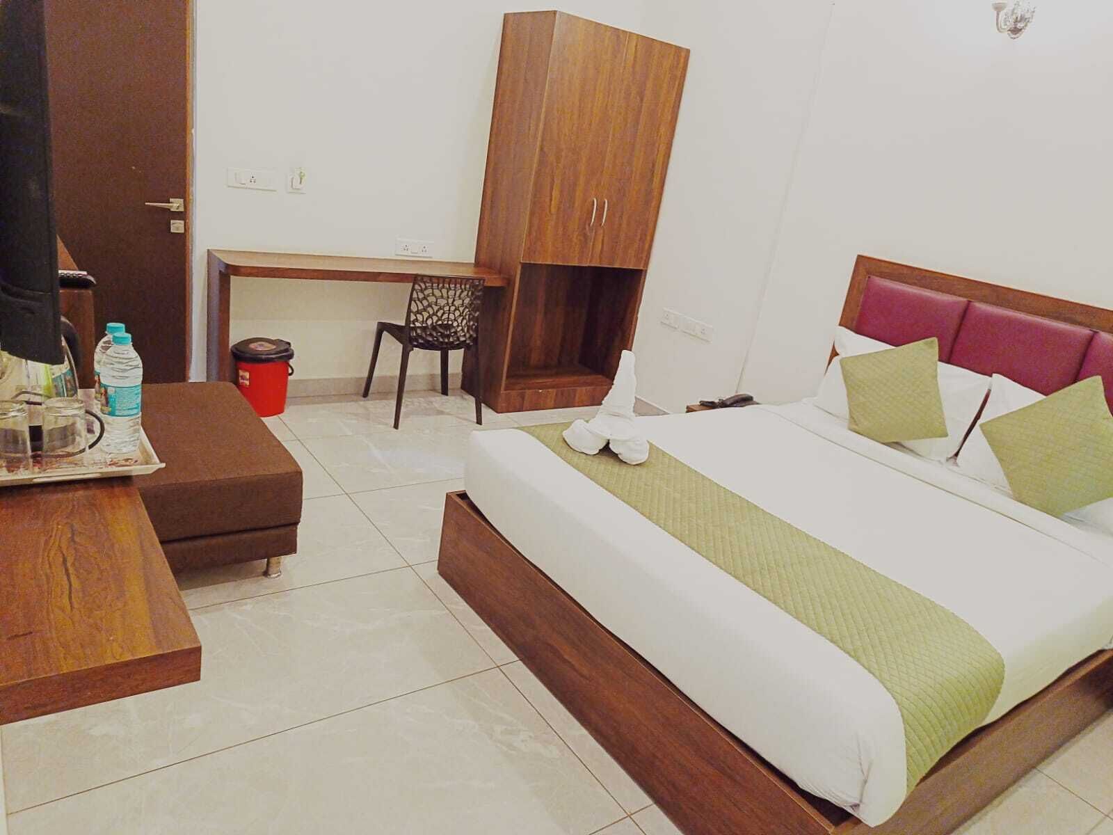 A hotel room with a bed, a desk, a chair, and a wardrobe.
