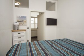 Ein Schlafzimmer mit Bett, Schminktisch, Fernseher und Fenster.