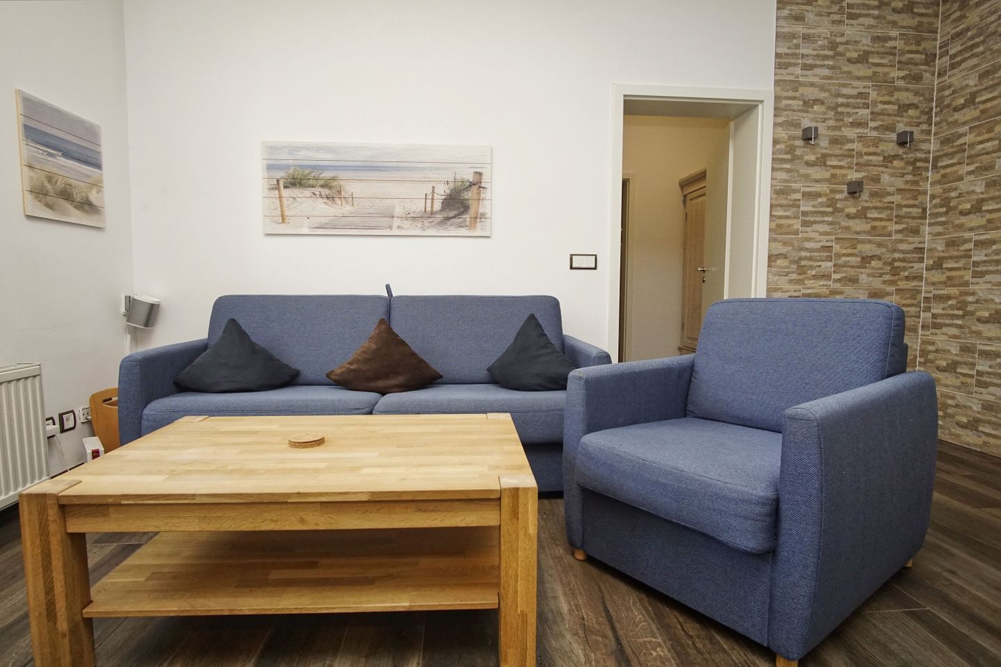 A living room with a blue sofa, a wooden coffee table, and a stone wall.