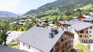 A mountainous village with traditional wooden houses, a winding road, and a clear view of the surrounding hills. - L`Altima Megève - Eclat des Veriaz (Megève)
