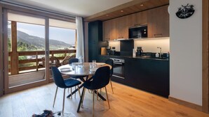 A modern kitchen with a dining area, large windows, and a view of the outdoors. - L`Altima Megève - Eclat des Veriaz (Megève)