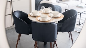 A dining area with a round table set for four, surrounded by dark chairs. - Meydan Apartment Sleeps 4 With Great Amenities (Dubai)