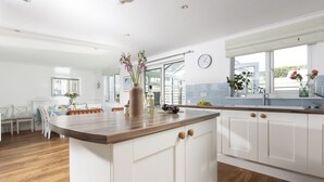 A modern kitchen with white cabinets, a wooden countertop, and a large window. - Little Tresevens is a generously sized detached home (Polzeath)
