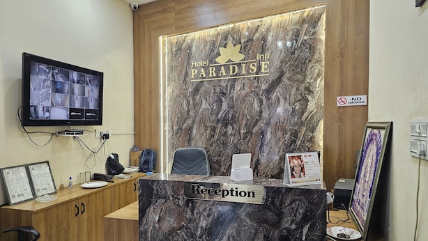 Una recepción con mostrador de mármol, un cartel de 'No Fumar', un reloj digital y un calendario.