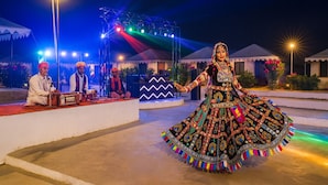 Una mujer vestida con traje tradicional actuando en un escenario con iluminación de colores.