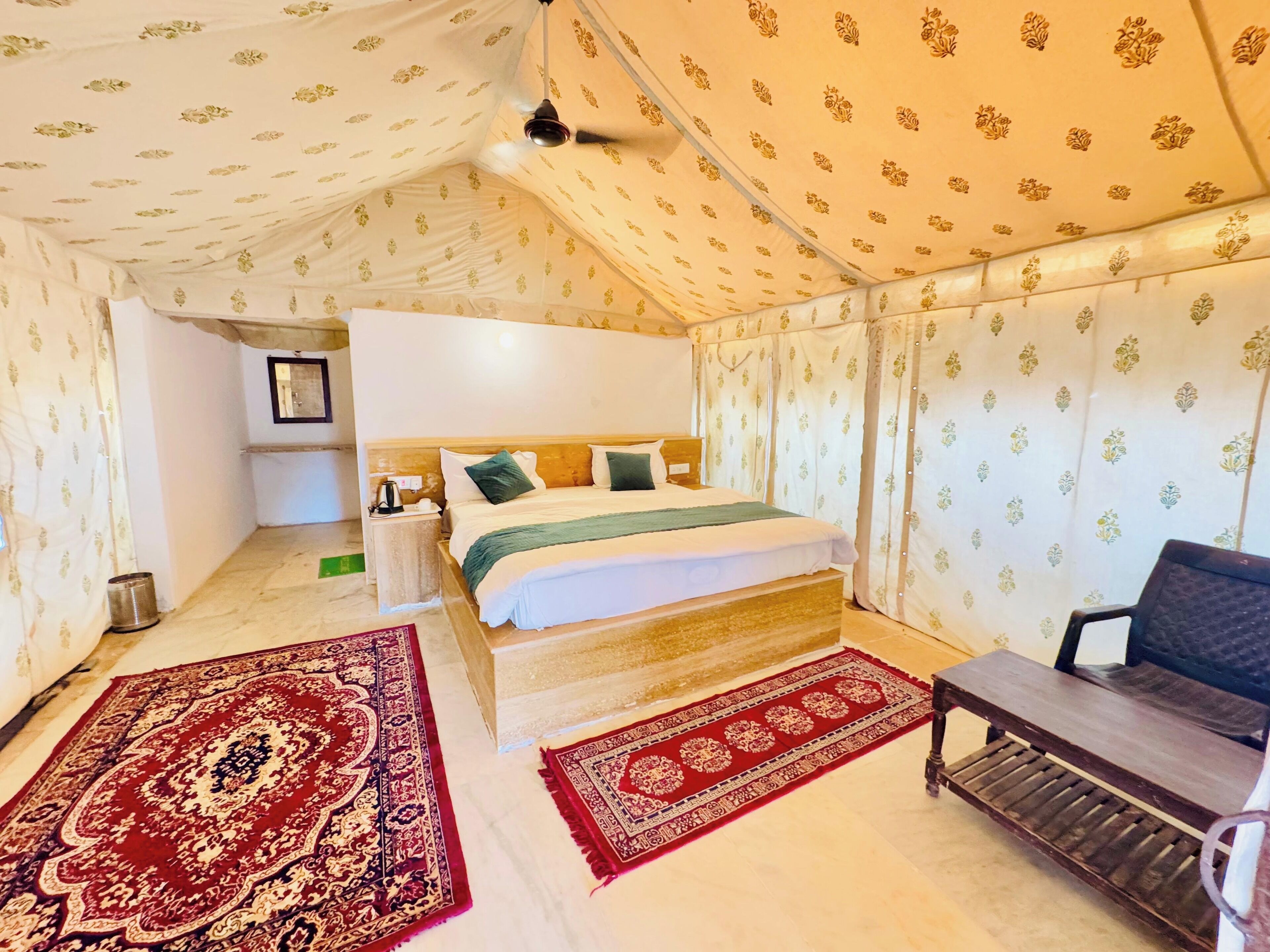 A bedroom with a bed, nightstand, and a chair. There are two rugs on the floor.