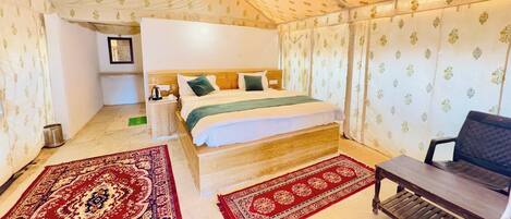 A bedroom with a bed, nightstand, and a chair. There are two rugs on the floor.