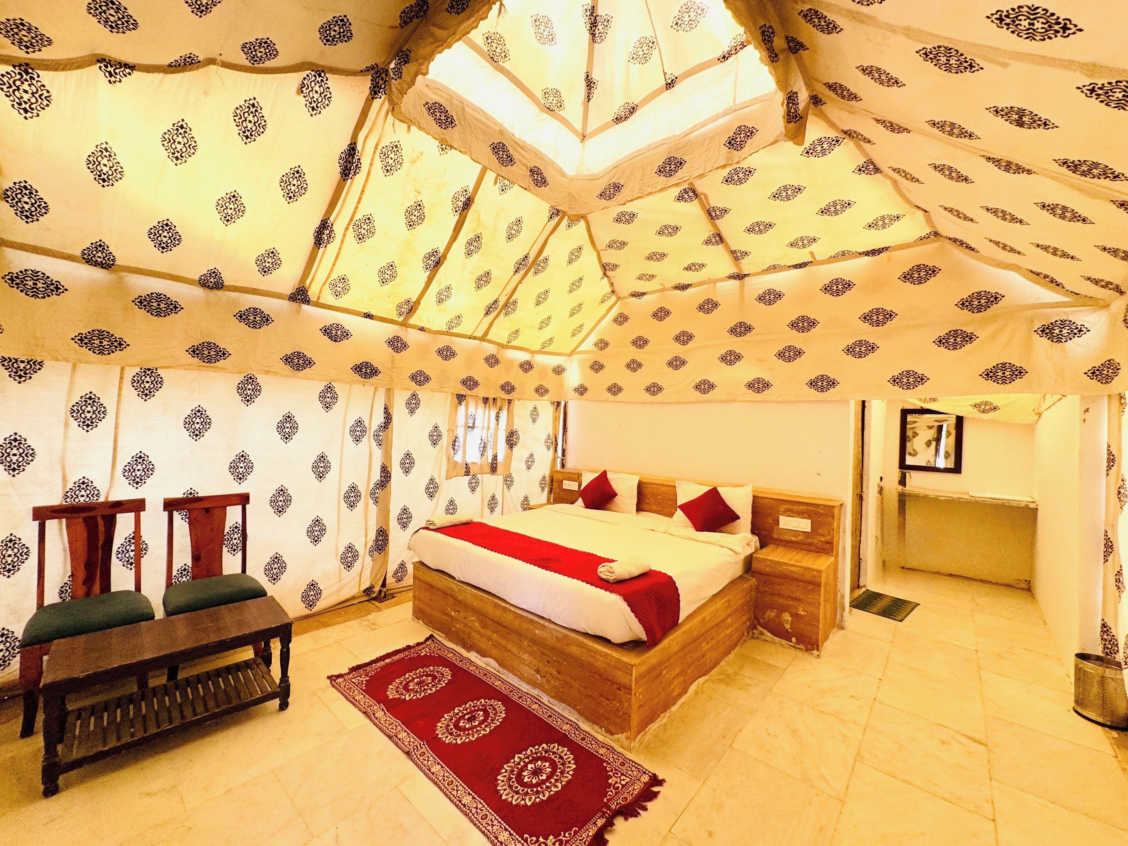 A tent-style room with a bed, wooden bench, and patterned curtains.