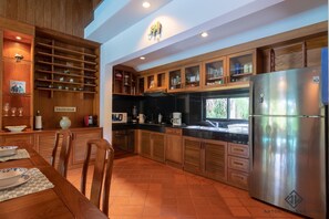 Eine moderne Küche mit Holzschränken, einem Edelstahlkühlschrank und einem Essbereich mit Tisch für zwei Personen.