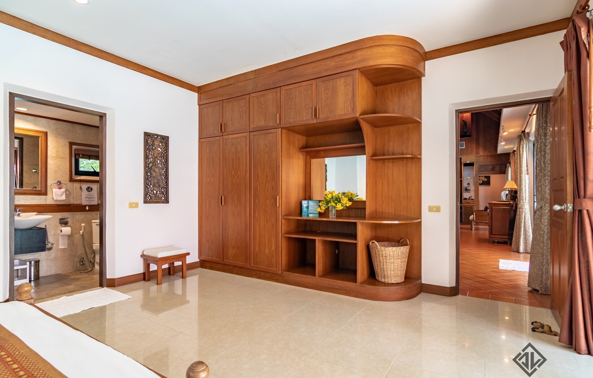 A spacious room with a large wooden wardrobe, a bench, and a small table with a vase of flowers.